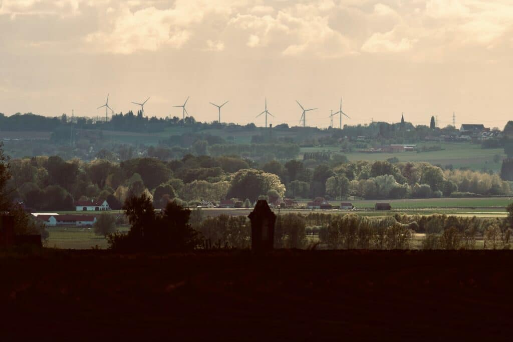 landscape of green bushes and fields with turbines near the top of the horizon
